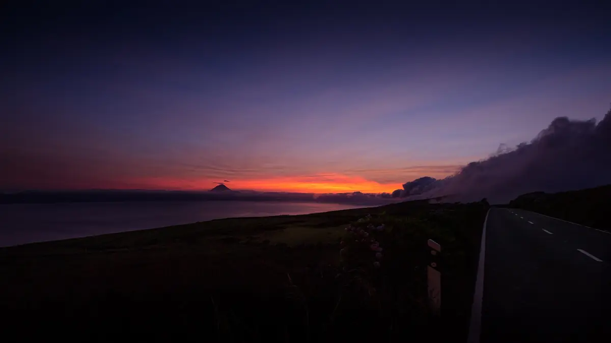 Red glow of sunset on the Atlantic horizon above a coastal road