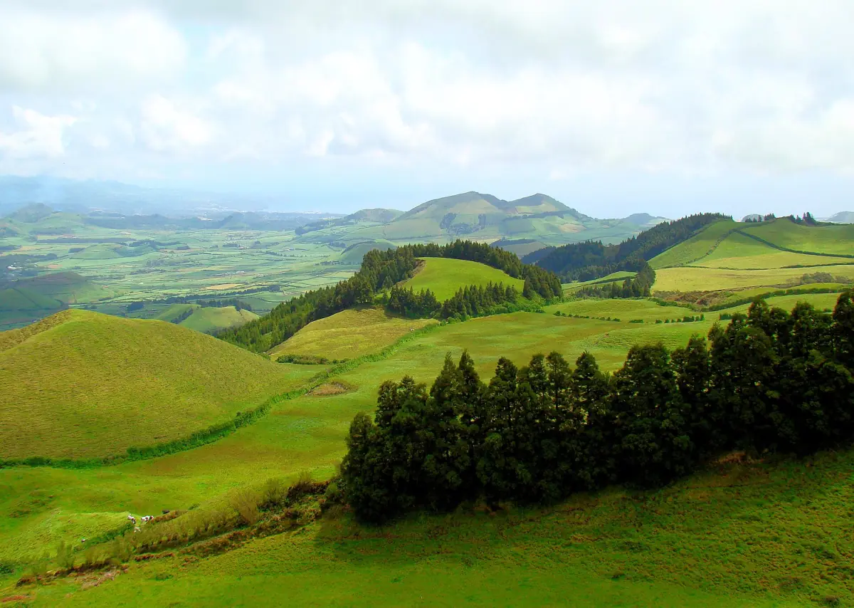 Rolling green hills and cones of São Miguel under a bright sky